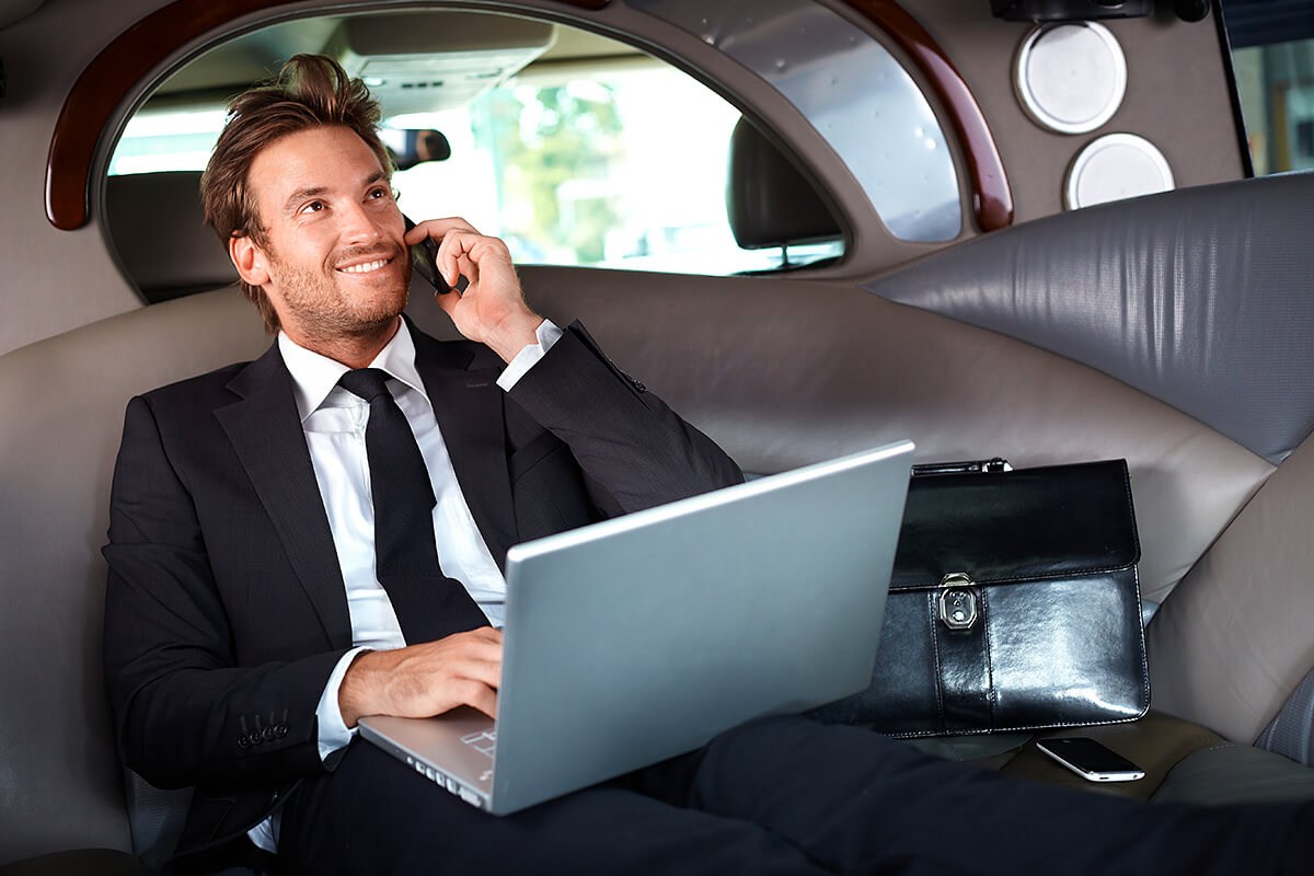 Businessman in car with laptop and phone Businessman in car with laptop and phone