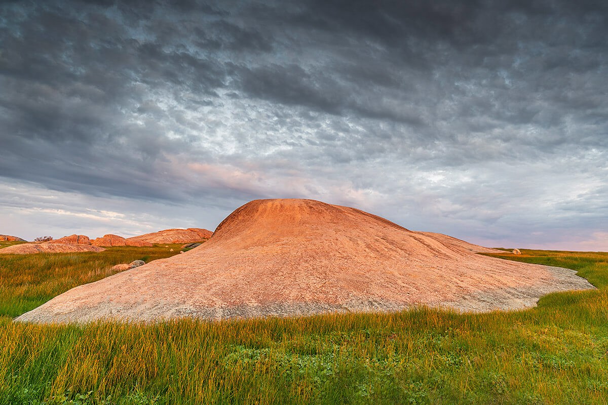 Image of a red rock surrounded by grass at sunset, city of Geelong Image of a red rock surrounded by grass at sunset, city of Geelong
