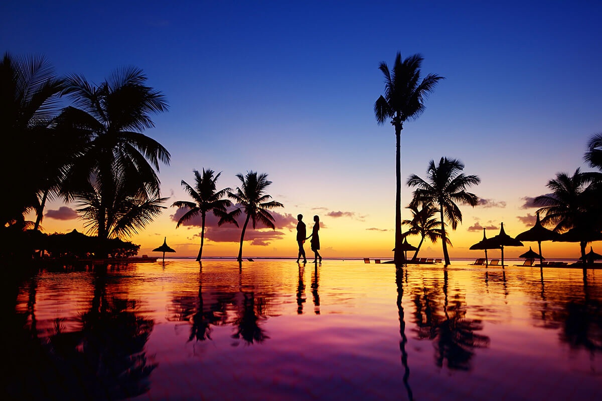 View of a romantic couple and palms by the Pacific Ocean during sunset View of a romantic couple and palms by the Pacific Ocean during sunset