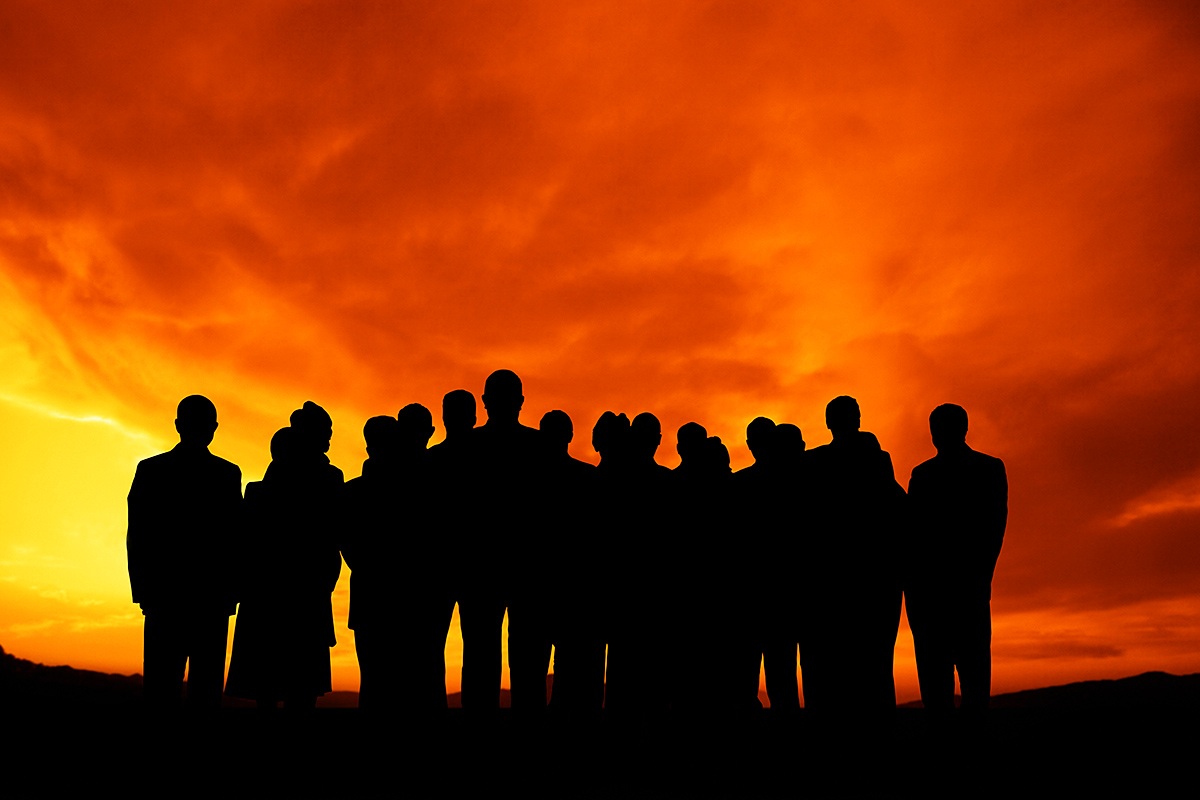 A large group of people stands at a bright sunset A large group of people stands at a bright sunset