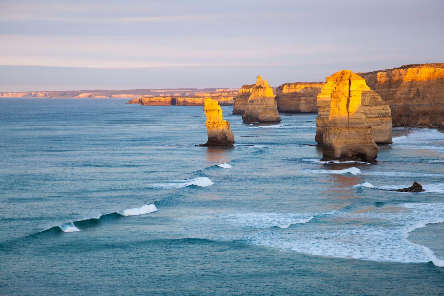This breathtaking coastal landscape captures the iconic rock formations bathed in the warm, ethereal glow of golden hour.
