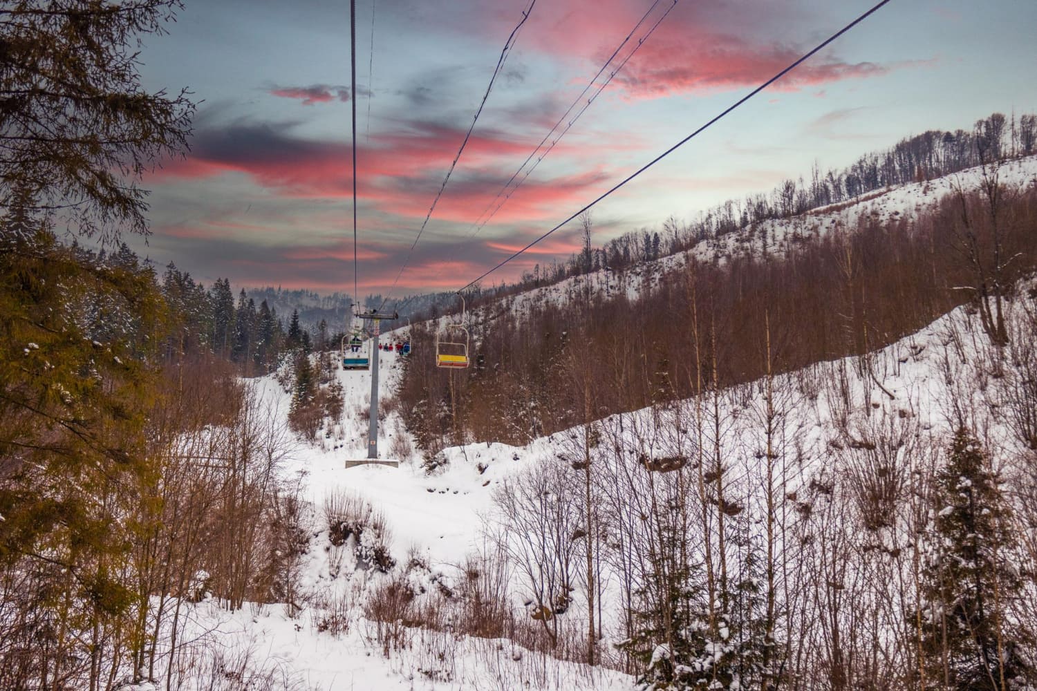 This enchanting photograph captures a ski resort during the magical golden hour of sunset, transforming the mountain landscape into a scene of pure romance and natural beauty.