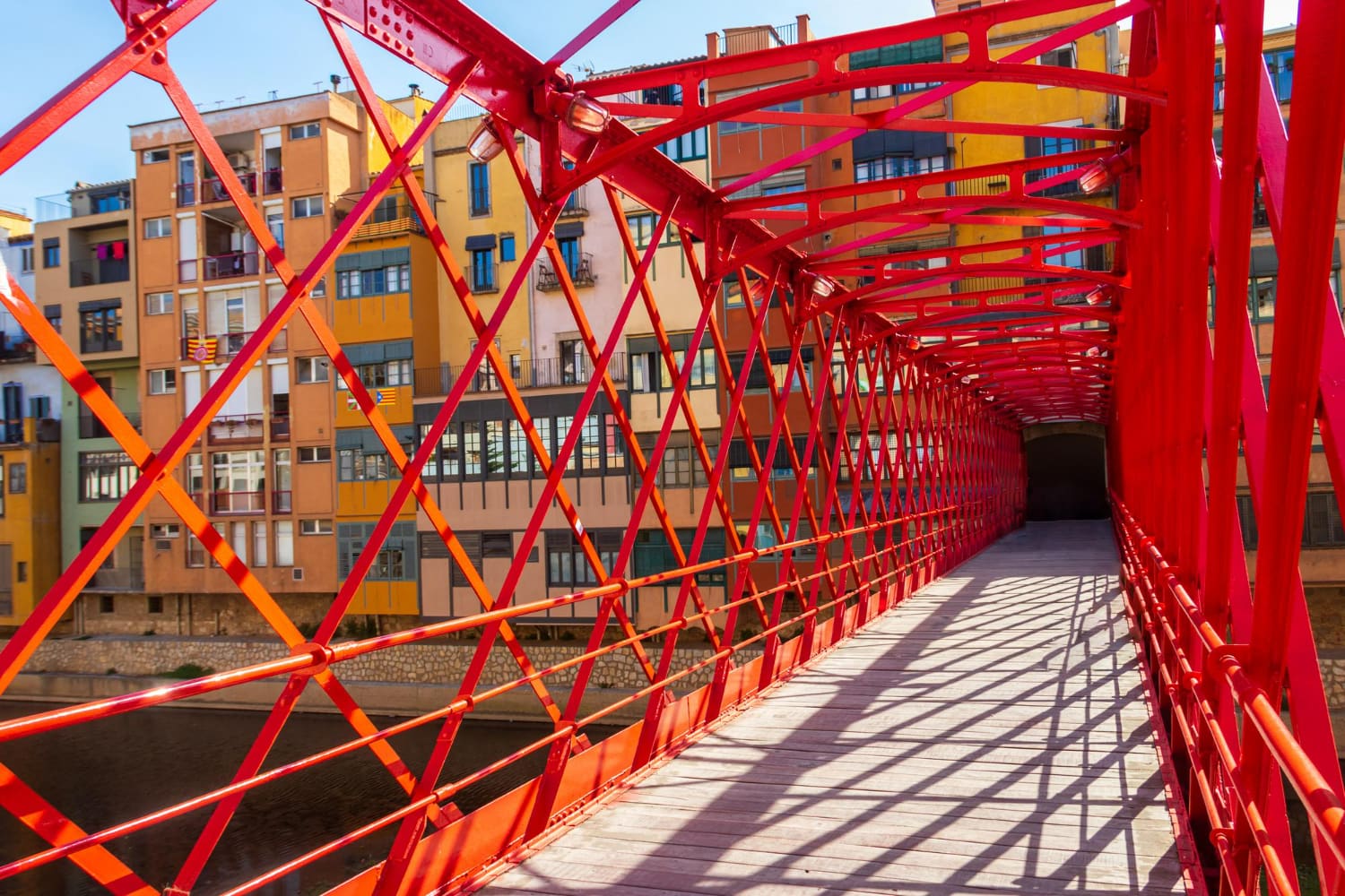 This striking photograph captures a stunning modern pedestrian bridge that serves as a bold architectural statement within a historic European urban landscape.