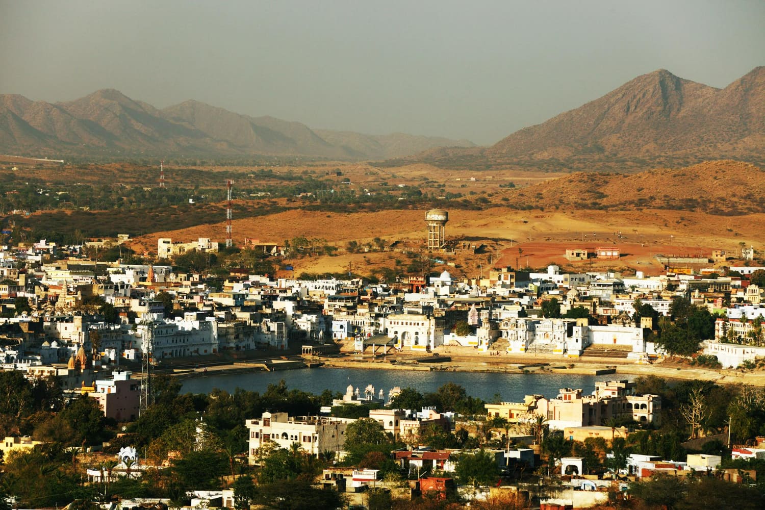 This breathtaking panoramic view captures a vibrant desert city nestled gracefully within a valley, framed by magnificent barren mountains that rise majestically on either side.