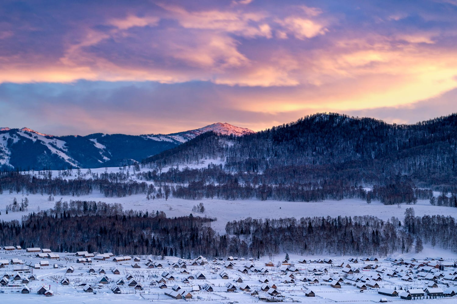 Nestled in the heart of majestic snow-covered mountains, a peaceful village emerges like a jewel against the pristine white landscape.