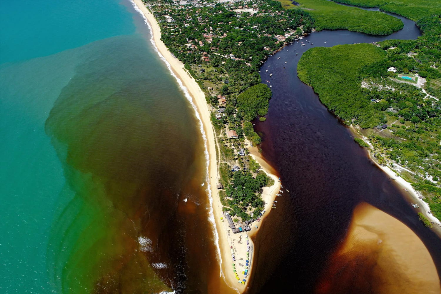 This breathtaking aerial photograph captures a stunning natural phenomenon where distinct water systems converge along a pristine coastline.