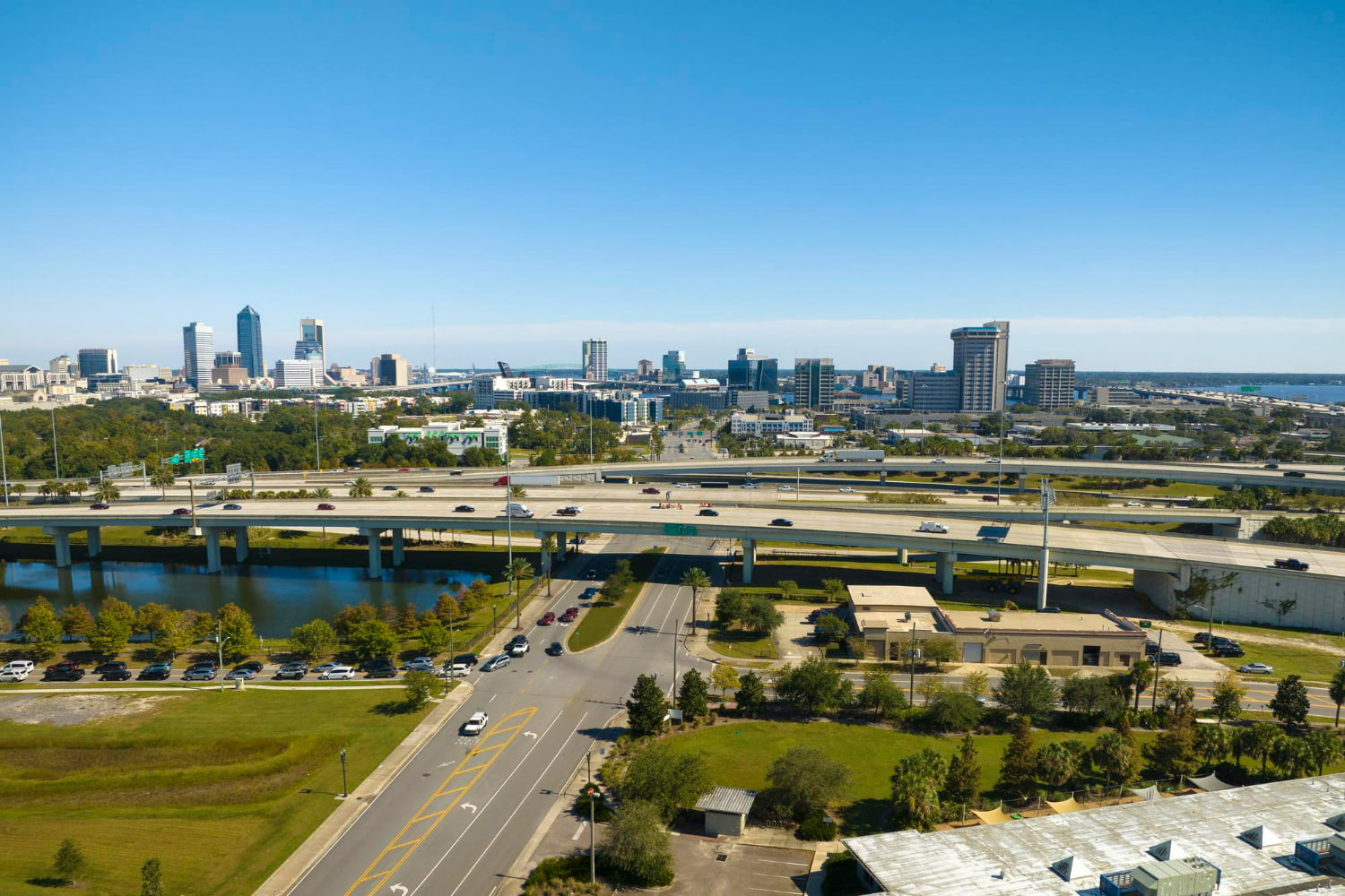 This sweeping aerial photograph captures the dynamic energy of a thriving metropolitan city sprawling across a landscape of water, highways, and green spaces.