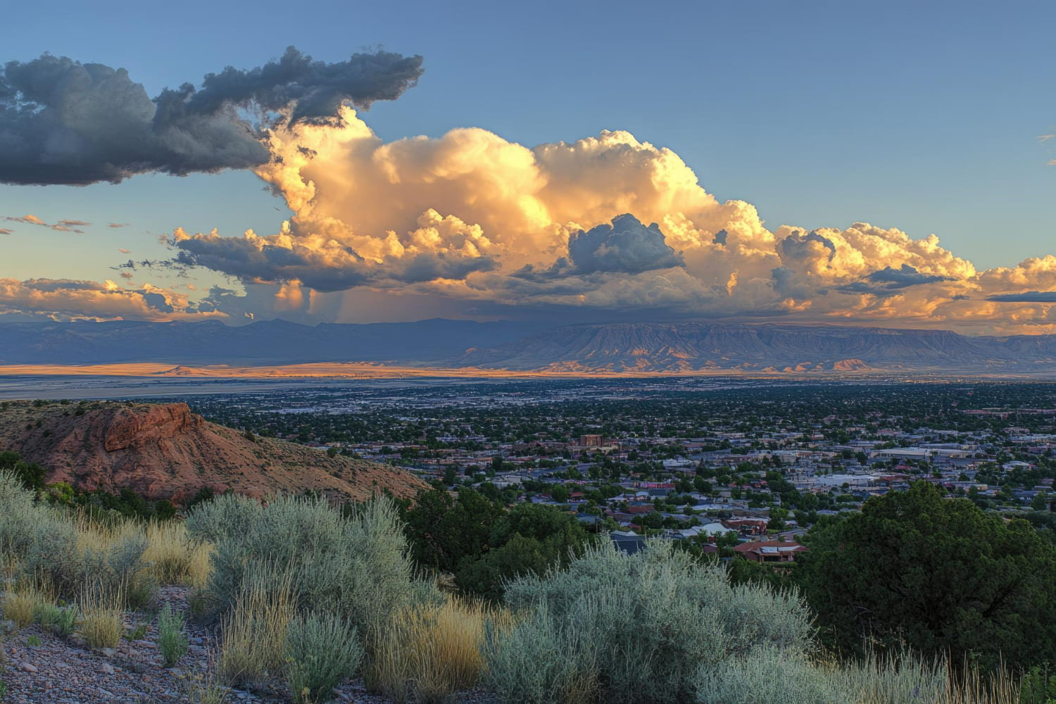 A spectacular panoramic landscape photograph capturing a sprawling valley city framed by dramatic geographical features and luminous skies.