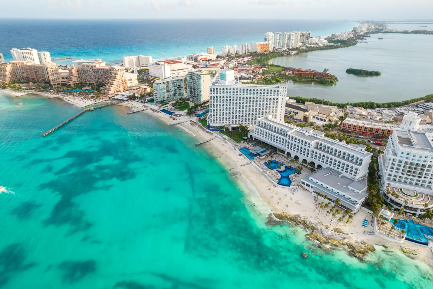 This stunning aerial drone photograph showcases a sprawling luxury all-inclusive beachfront resort nestled along a pristine stretch of Caribbean coastline.