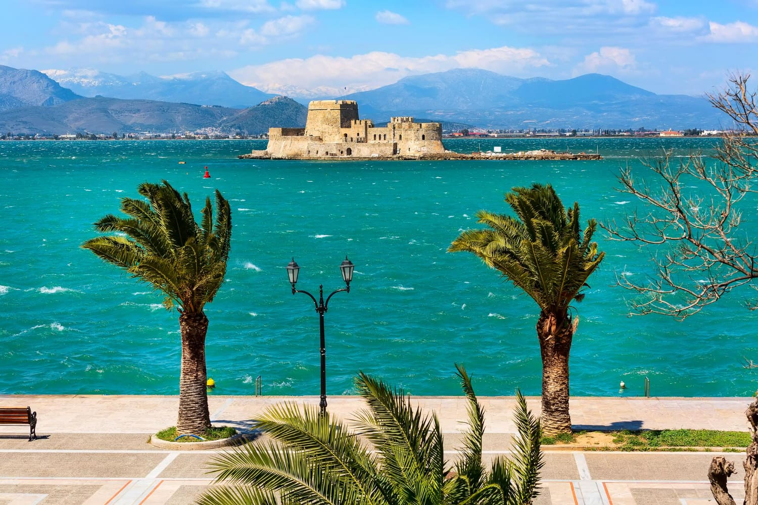 The composition perfectly showcases the harmony between historic architecture, natural landscape, and the sparkling sea.